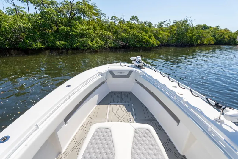 Slide: The Image of 2025 Invincible 33 Open Fisherman boat on calm water near lush greenery. - 35