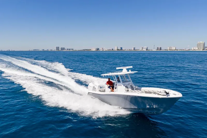 Slide: The Image of Invincible 33 Open Fisherman 2025 navegando en mar abierto, ciudad costera al fondo. - 67