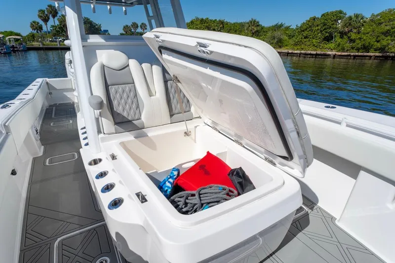 Slide: The Image of 2025 Invincible 33 Open Fisherman boat with open storage compartment, docked by lush greenery. - 37