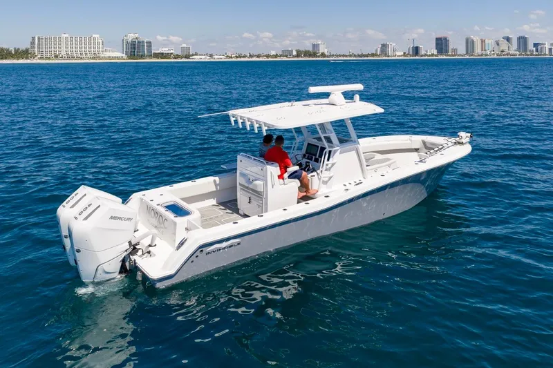 Slide: The Image of 2025 Invincible 33 Open Fisherman boat cruising on blue ocean near city skyline. - 56