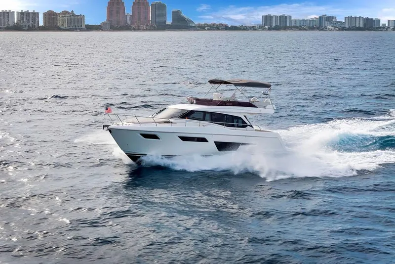 Slide: The Image of 2021 Ferretti Yachts 500 cruising on open water with city skyline in background. - 19