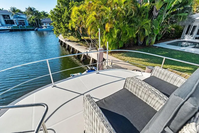 Slide: The Image of 2009 Carver 56 Voyager SE yacht deck with wicker chairs, overlooking serene waterfront and lush greenery. - 43