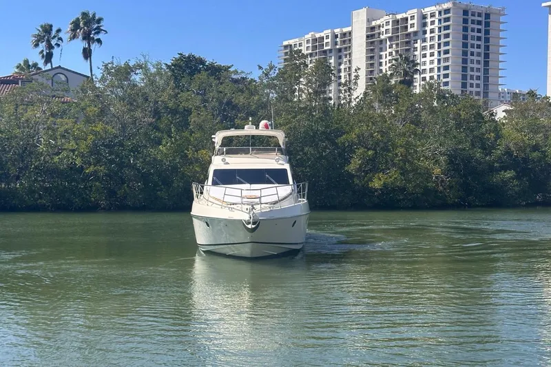 Slide: The Image of 2007 Azimut 55E yacht cruising on a calm river with lush greenery and buildings in the background. - 3