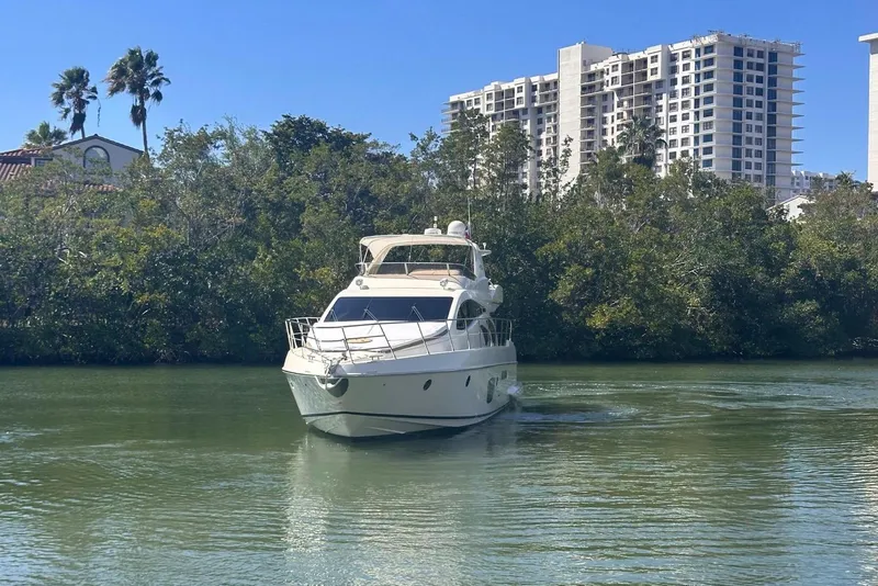 Slide: The Image of 2007 Azimut 55E yacht cruising on a calm river with lush greenery and buildings in the background. - 4
