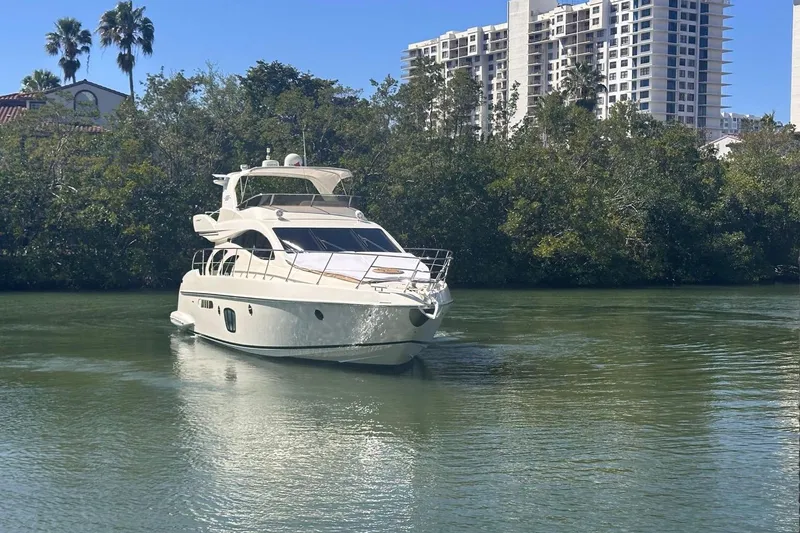 Slide: The Image of 2007 Azimut 55E yacht cruising on a calm river with lush greenery and buildings in the background. - 5