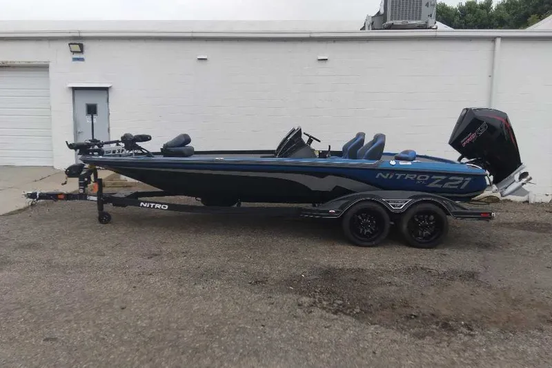 Slide: The Image of 2027 Nitro Z21 XL Pro bass boat on trailer, parked beside a white building. - 1