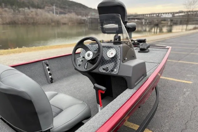 Slide: The Image of 2027 Tracker Bass Tracker Classic XL boat interior with steering wheel and dashboard by a river. - 14