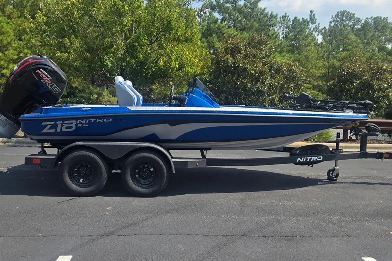 The Image of 2027 Nitro Z18 XL Pro boat on trailer, blue and white design, parked outdoors. - 0
