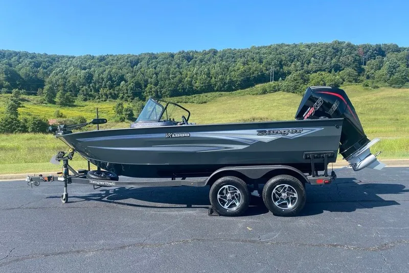 The Image of 2026 Ranger VX1888 WT boat on trailer, parked on asphalt with scenic green hills. - 0
