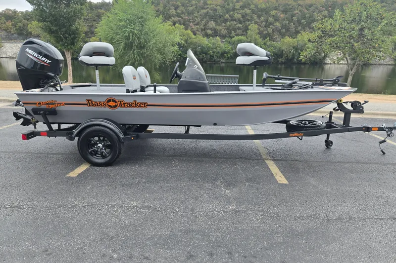 The Image of 2027 Tracker Bass Tracker Classic Limited boat on trailer, parked near a lake. - 0