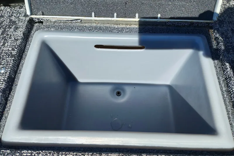 Slide: The Image of 2025 Tracker Targa V-18 WT livewell, open lid, gray interior, textured surrounding surface. - 22
