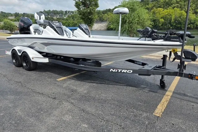 Slide: The Image of 2027 Nitro Z21 XL Pro boat on trailer, parked near a lake with lush greenery. - 2