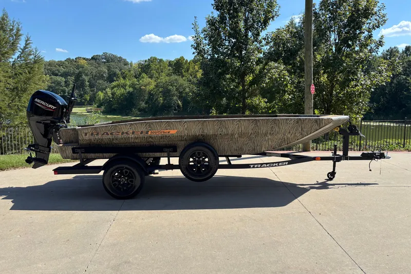 The Image of 2027 Tracker Grizzly 1756 T Marsh boat on trailer, parked outdoors with trees in background. - 0