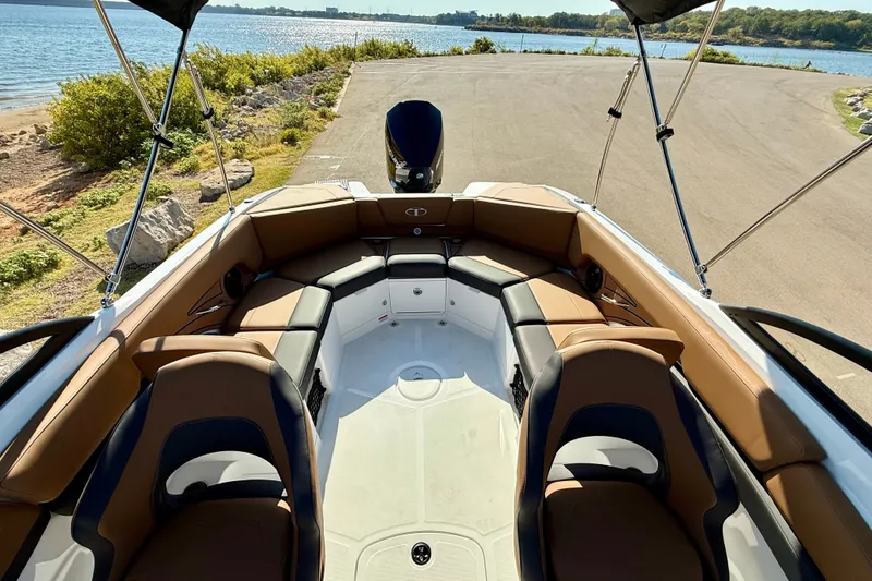 Slide: The Image of 2027 Tahoe 210 S boat interior with tan seating, near a scenic waterfront. - 21
