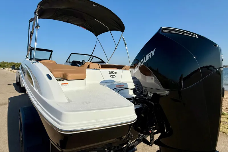 Slide: The Image of 2027 Tahoe 210 S boat with Mercury engine, parked near a waterfront. - 23