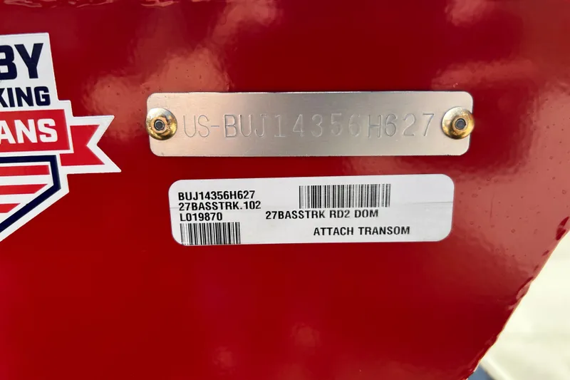 Slide: The Image of 2027 Tracker Bass Tracker Classic XL boat identification plate and barcode on red surface. - 67