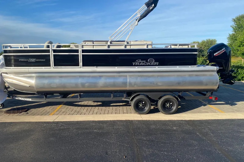 The Image of 2027 Sun Tracker Fishin' Barge 22 DLX pontoon boat on trailer, side view. - 0