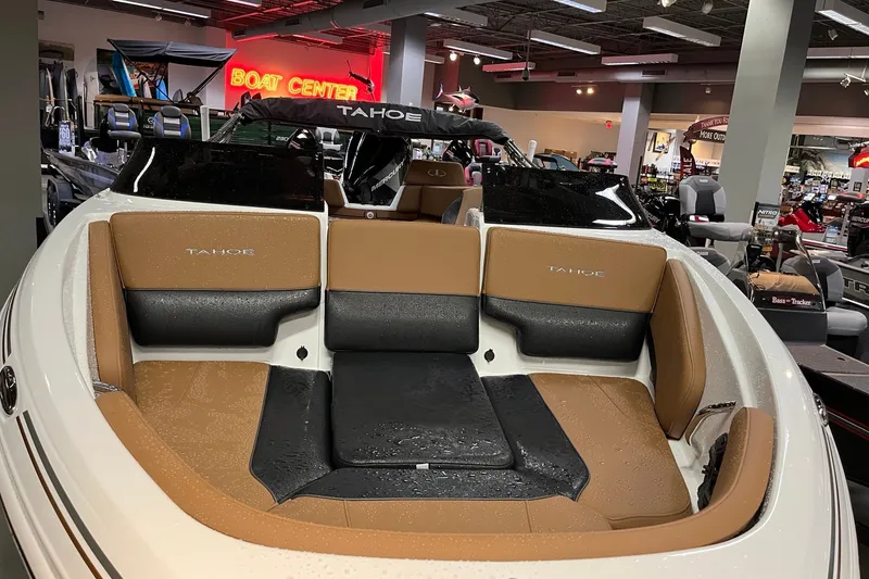 Slide: The Image of 2027 Tahoe 210 S boat interior with tan and black seating at a showroom. - 8