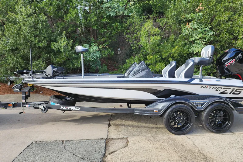 The Image of 2027 Nitro Z18 XL Pro boat on trailer, parked outdoors with lush greenery background. - 0