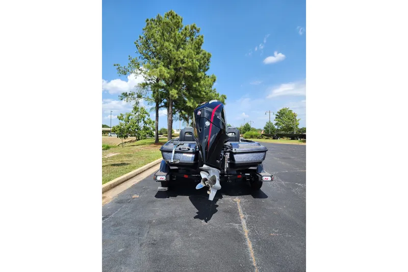 Slide: The Image of 2027 Nitro Z21 XL Pro boat parked on asphalt, surrounded by trees under a clear blue sky. - 2