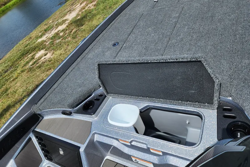 Slide: The Image of 2027 Nitro Z21 XL Pro boat storage compartment with open lid, near a grassy shoreline. - 12