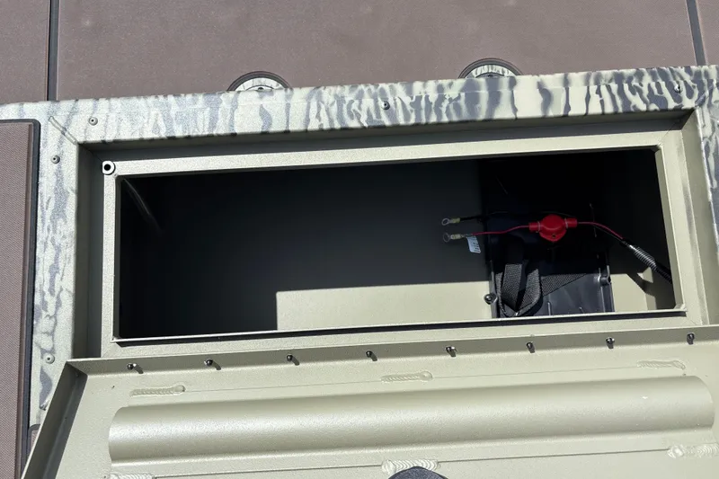 Slide: The Image of Open storage compartment in 2027 Tracker Grizzly 1860 CC boat, showing wiring and battery setup. - 19