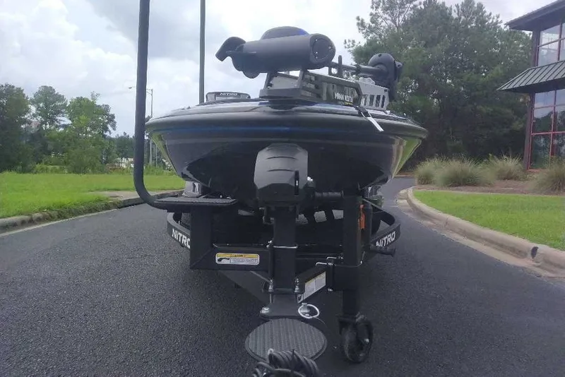 Slide: The Image of 2027 Nitro Z21 XL boat on trailer, parked on asphalt near greenery and building. - 8