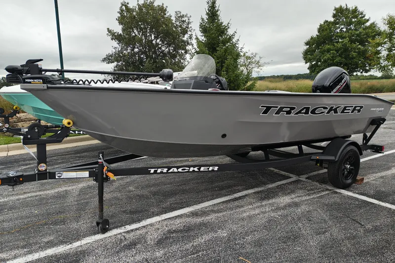 The Image of 2027 Tracker Pro Guide V-16 SC fishing boat on trailer, parked outdoors. - 1