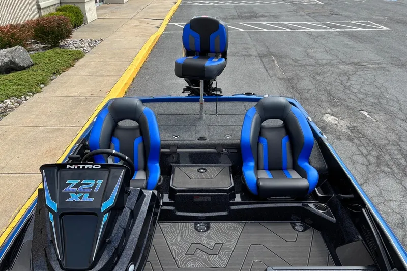 Slide: The Image of 2027 Nitro Z21 XL boat interior with blue and black seating, parked on pavement. - 5