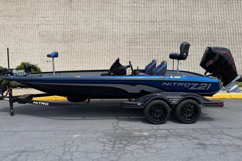 The Image of 2027 Nitro Z21 XL boat on trailer, blue and black design, parked outdoors. - 0