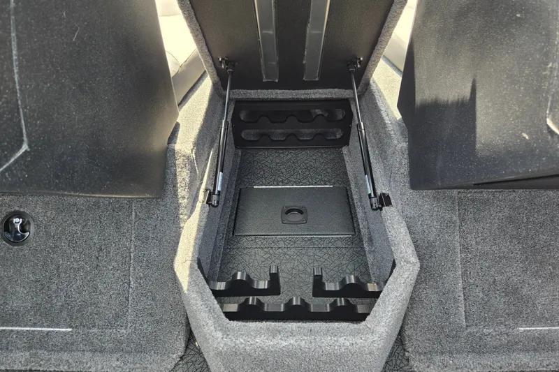 Slide: The Image of 2027 Tracker Targa V-18 Combo boat storage compartment with rod holders and carpeted interior. - 18