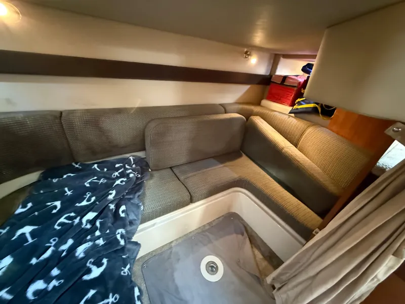 Slide: The Image of 2005 Cruisers Yachts 340 Express interior with cozy seating and nautical-themed blanket. - 25
