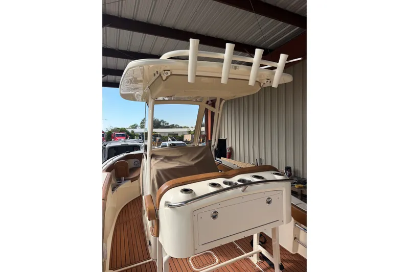 Slide: The Image of 2024 Scout 240 XSF boat interior with rod holders and seating under a covered dock. - 9