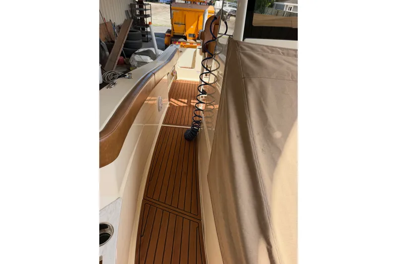Slide: The Image of 2024 Scout 240 XSF boat interior with teak flooring and beige cover. - 18