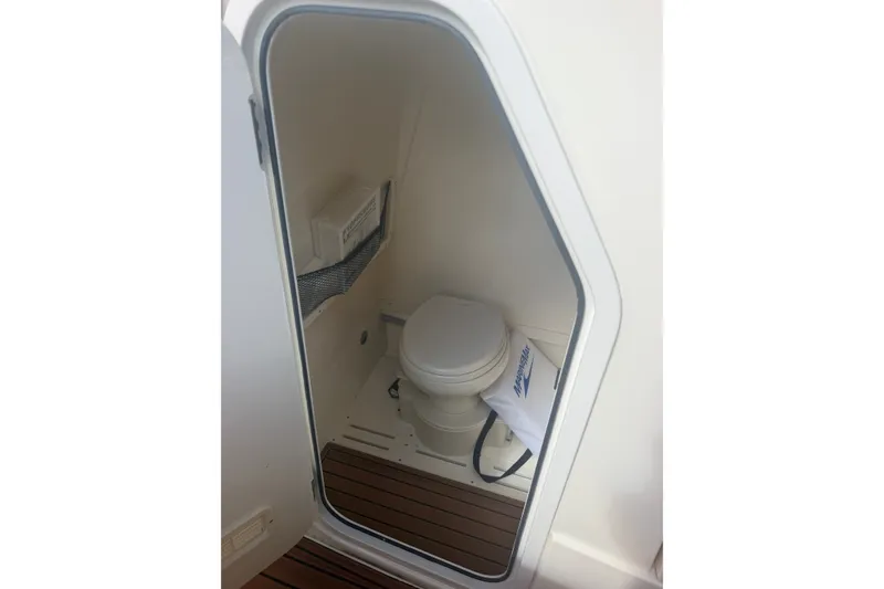 Slide: The Image of 2024 Scout 240 XSF boat interior with compact marine toilet and wooden flooring. - 37