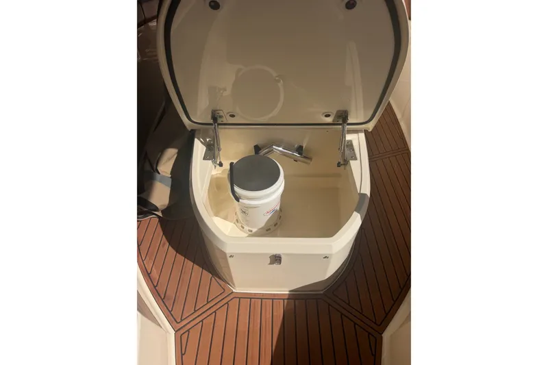 Slide: The Image of Open storage compartment on 2024 Scout 240 XSF boat with a bucket inside. - 33