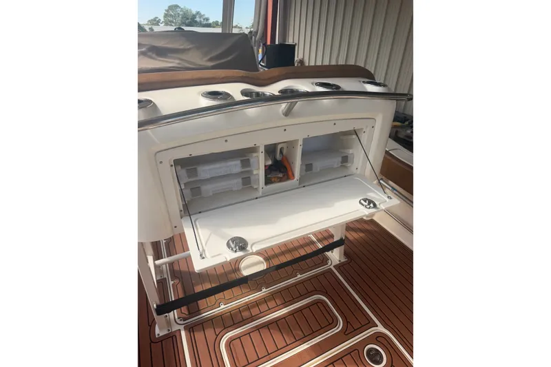 Slide: The Image of 2024 Scout 240 XSF boat interior with open storage compartment and teak flooring. - 20