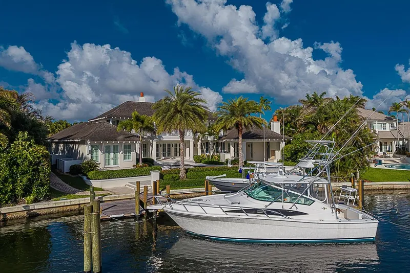 Slide: The Image of 2008 Bertram 360 yacht docked by luxurious waterfront home, surrounded by palm trees and blue sky. - 50