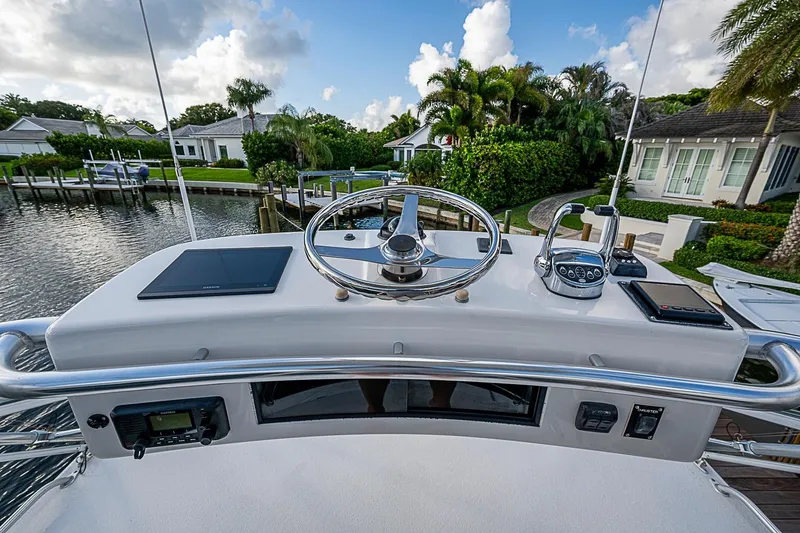 Slide: The Image of Helm of 2008 Bertram 360 yacht with steering wheel and controls, docked by waterfront homes. - 62