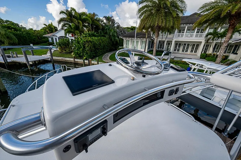 Slide: The Image of 2008 Bertram 360 yacht helm with modern controls, docked near a luxurious waterfront property. - 63