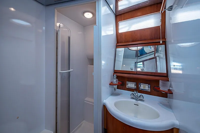Slide: The Image of Luxurious bathroom in a 2008 Bertram 360 yacht, featuring a shower and elegant wood accents. - 14