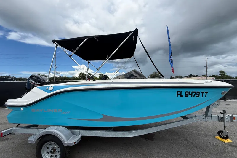 Slide: The Image of 2024 Bayliner Element M17 boat with blue hull on trailer, under cloudy sky. - 1