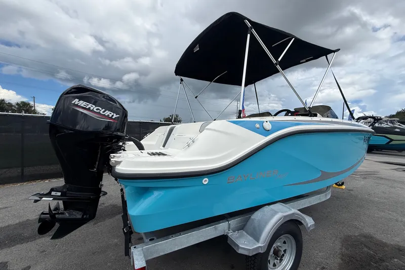 Slide: The Image of 2024 Bayliner Element M17 boat with Mercury engine on trailer, under cloudy sky. - 2