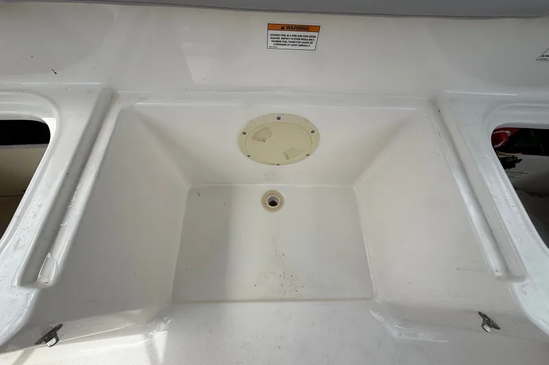 Slide: The Image of 2024 Bayliner Element M17 boat storage compartment with drainage and warning label. - 43