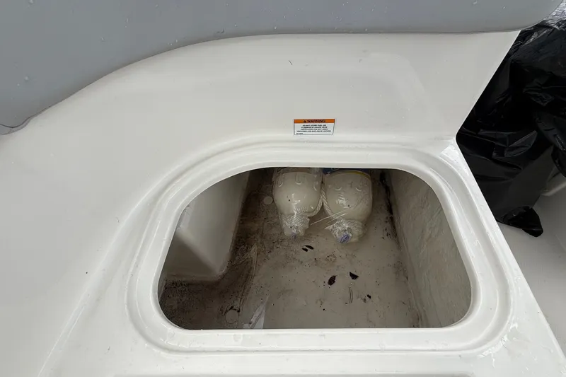 Slide: The Image of An open storage compartment in the Bayliner Element M17 with two water bottles and some dirt. - 23