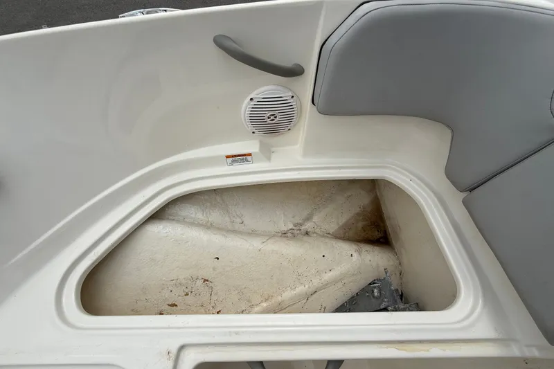 Slide: The Image of An open storage compartment in a Bayliner Element M17 boat with gray upholstery. - 32