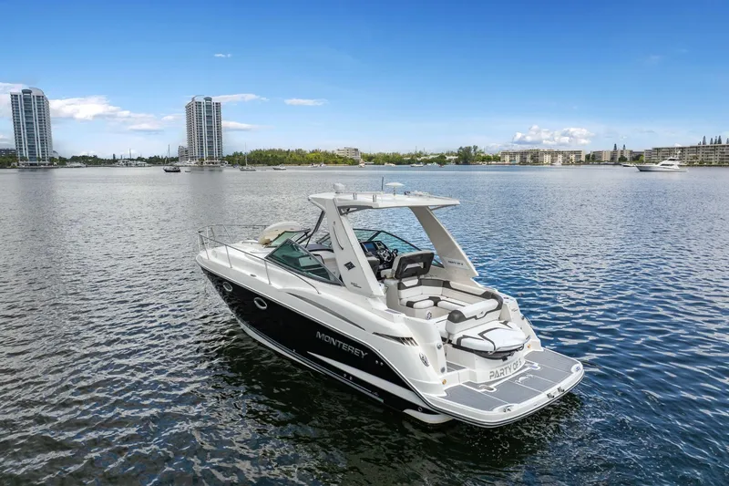 Slide: The Image of 2014 Monterey 320 Sport Yacht on calm water with city skyline backdrop. - 2