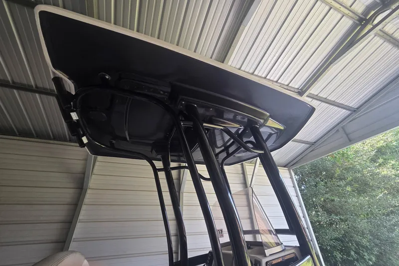 Slide: The Image of 2019 Robalo 226 Cayman boat T-top under a metal shelter. - 17