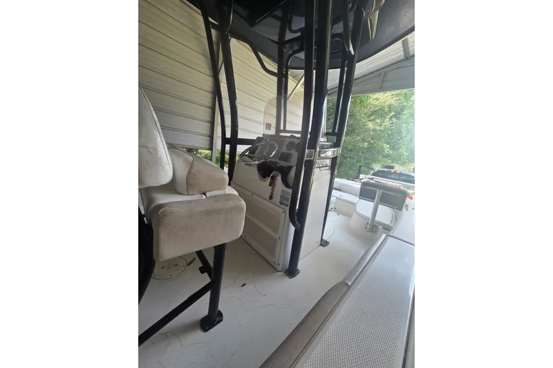 Slide: The Image of 2019 Robalo 226 Cayman boat interior with seating and console, parked under shelter. - 6