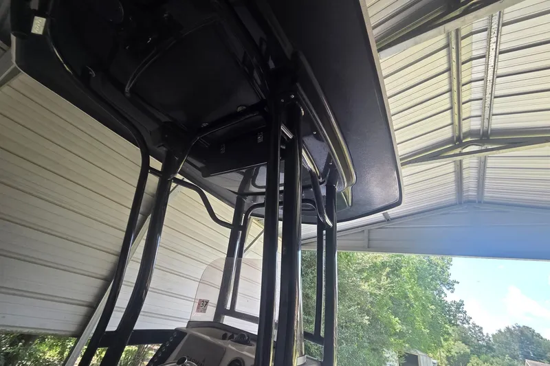 Slide: The Image of 2019 Robalo 226 Cayman boat under metal shelter, showcasing T-top structure. - 18